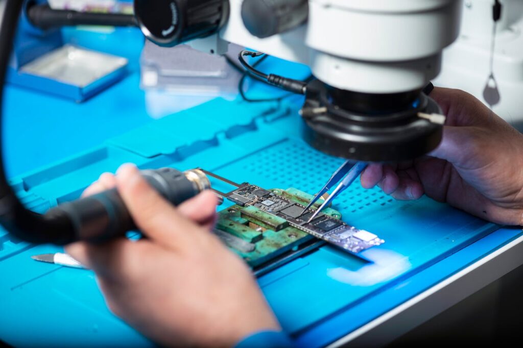 Close-up of technician repairing electronic circuit board under a microscope in Toronto lab.