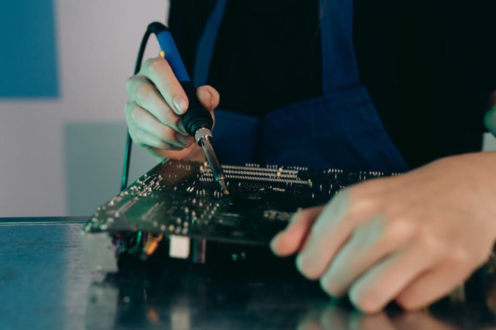 Close-up view of hands soldering electronic components on a circuit board.